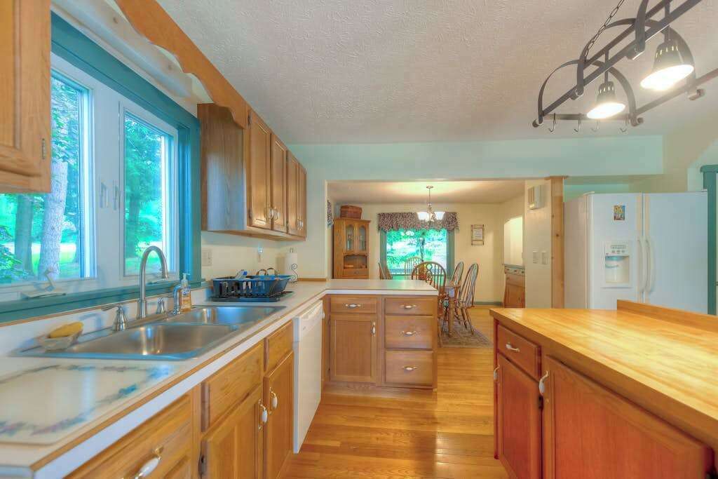 A kitchen with wooden cabinets, a marble countertop, and a sink.