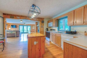 Une cuisine spacieuse avec des meubles en bois, un îlot central et un four à micro-ondes.