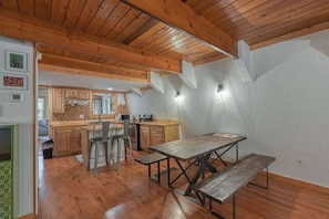Une cuisine rustique avec des meubles en bois, une table à manger et un plafond haut avec des poutres apparentes.