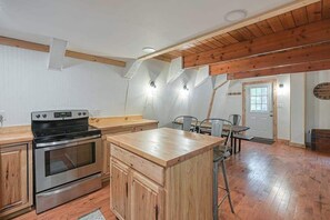 Una cocina con armarios de madera, estufa de acero inoxidable y una isla de madera.