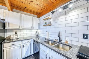 Eine moderne Küche mit weißen Schränken, Granit Arbeitsplatten, einer Spüle und Holzbalken an der Decke.