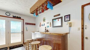 A bar area with stools, a wooden counter, and a mirror. - Rustic 3BR Cabin - HOT TUB - Oakland (Oakland)