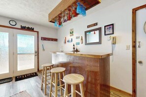 Un'area bar con sgabelli, un bancone in legno e uno specchio.