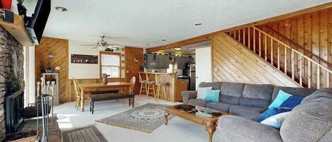 A living room with a fireplace, a sofa, a coffee table, and a dining area with a wooden table and chairs.