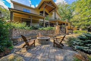 Ein modernes Haus mit Natursteinfassade, überdachter Veranda und Feuerstelle.