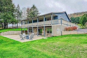 A two-story building with a balcony, a patio with outdoor furniture, and a stone facade.