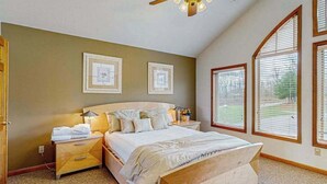 Ein Schlafzimmer mit einem großen Bett, einem Nachttisch, einem Deckenventilator und gerahmten Bildern an der Wand.