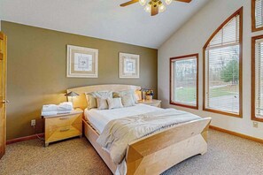 Ein Schlafzimmer mit einem großen Bett, einem Nachttisch, einem Deckenventilator und gerahmten Bildern an der Wand.