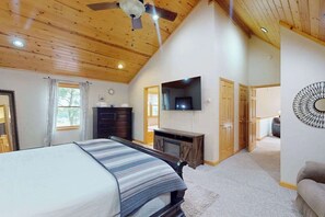 Ein Schlafzimmer mit Bett, Fernseher, Kommode und Deckenventilator.