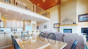 A spacious living area with a dining table, chairs, a sofa, and a fireplace.