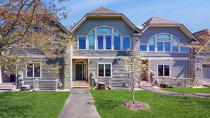 A two-story residential building with a central entrance, a small porch, and a well-maintained lawn.