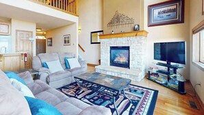 A spacious living room with a fireplace, a television, and a balcony.