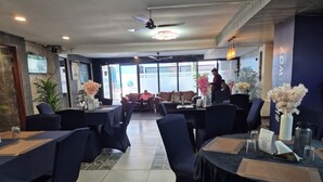 Un restaurante con mesas y sillas, un ventilador de techo y vistas al exterior.