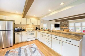 Uma cozinha moderna com armários brancos, eletrodomésticos de aço inoxidável e bancada de granito.