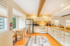 A modern kitchen with wooden cabinets, stainless steel appliances, and a dining area with a table and chairs.
