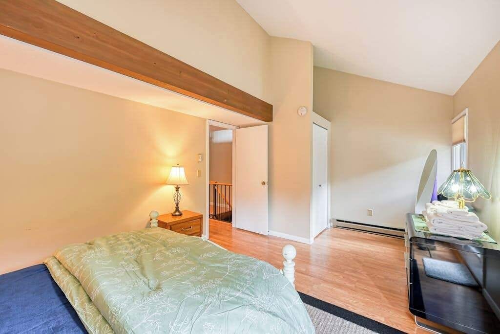 Un dormitorio con cama, mesita de noche, lámpara y vistas a una escalera que lleva a otra habitación.