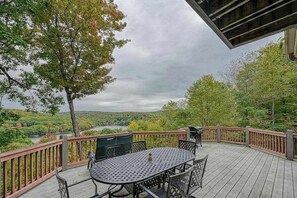 Eine Terrasse mit Tisch und Stühlen mit Blick auf einen Fluss und eine bewaldete Landschaft.