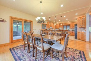A spacious kitchen with wooden cabinets, a large dining table, and a chandelier.