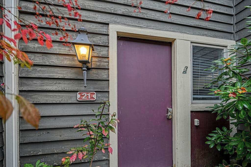 A house with a purple door, a number sign, and a lamp post.
