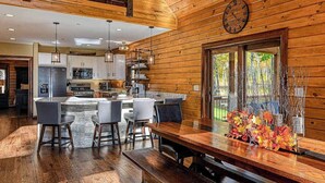 A spacious kitchen with a central island, wooden walls, and a large window. - Charming 6BR Chalet - HOT TUB - Mountain View (McHenry)