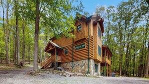 Eine Blockhütte mit Stein Fundament, einer Veranda und einer Treppe, die zu einer Terrasse führt.