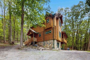 A log cabin with a stone foundation, a porch, and a staircase leading to a deck. - Rustic 5BR Cabin - HOT TUB - Swanton (Swanton)