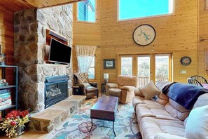A cozy living room with a stone fireplace, leather sofas, a flat-screen TV, and a large clock on the wall. - Charming 4BR Townhouse - LAKE VIEW - McHenry (McHenry)