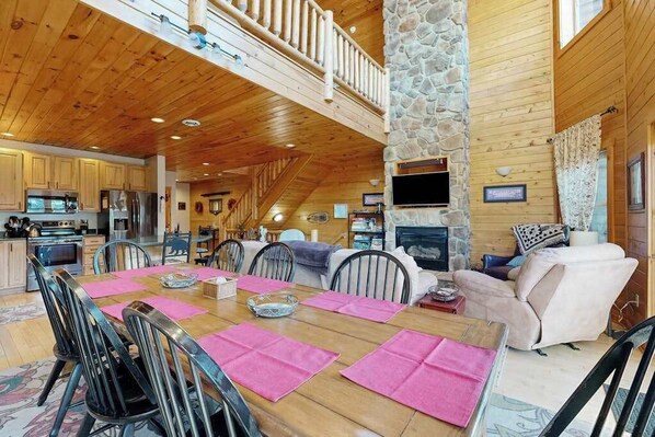A spacious wooden cabin interior with a dining area, kitchen, and living room.