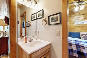 A bathroom with a white sink, wooden cabinets, a mirror, and framed pictures on the wall.