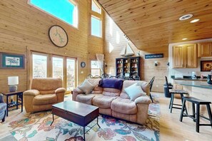 A spacious living area with a large sofa, a coffee table, and a dining area with a kitchen in the background. - Charming 4BR Townhouse - LAKE VIEW - McHenry (McHenry)