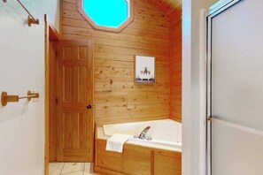 A wooden-paneled bathroom with a bathtub, a door, and a small window. - Charming 4BR Townhouse - LAKE VIEW - McHenry (McHenry)