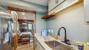Una cocina compacta con lavamanos integrado, una zona de comedor con mesa y sillas, y un refrigerador.