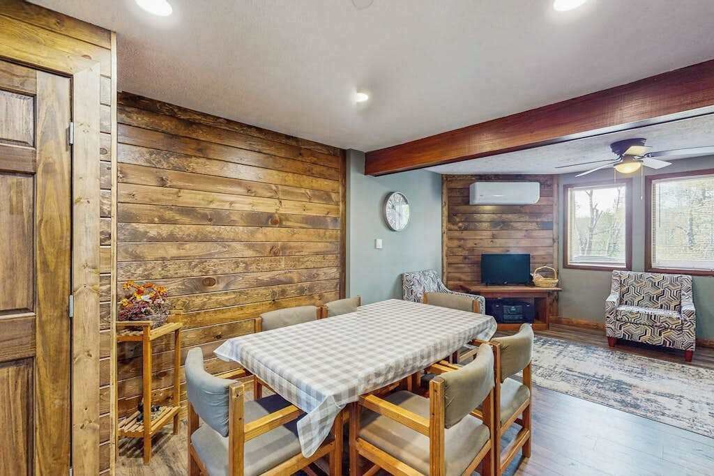 Un comedor con una mesa y sillas, un televisor y un sillón estampado.