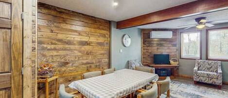 Un comedor con una mesa y sillas, un televisor y un sillón estampado.