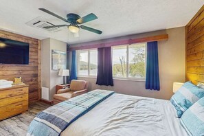 A bedroom with a bed, a chair, a dresser, a ceiling fan, and a window with curtains. - 2BR - Cozy - Lakefront - Hot Tub (McHenry)