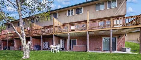 A two-story building with a covered patio, a hot tub, and a brick exterior.