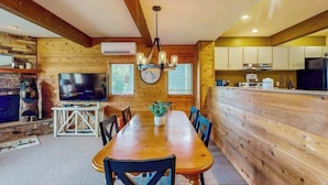 Un intérieur en bois comprenant une table à manger, des chaises, un téléviseur et un coin cuisine.