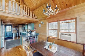 Ein Holzblockhaus mit Essbereich, Küche und einem großen Fenster.