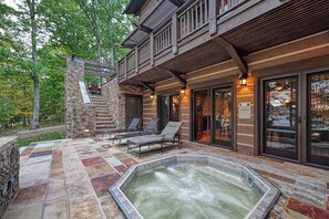 A spa area with a hot tub, stone flooring, and outdoor seating. - Lakefront 7BR Chalet - HOT TUB - Swanton (Swanton)