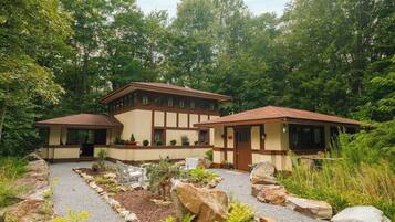 A two-story building with a symmetrical facade, a covered porch, and a gravel pathway leading to the entrance.
