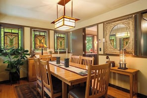 A dining area with a wooden table, chairs, and a hanging light fixture.