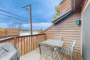 A wooden deck with a table and chairs, a barbecue grill, and a view of the surrounding area. - 3BR - Lakeside Retreat - Pool (McHenry)
