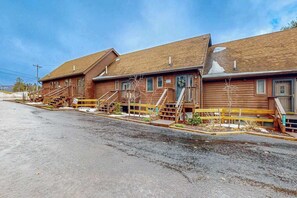 Une rangée de cabanes en bois, chacune dotée d’un escalier extérieur menant à l’entrée.