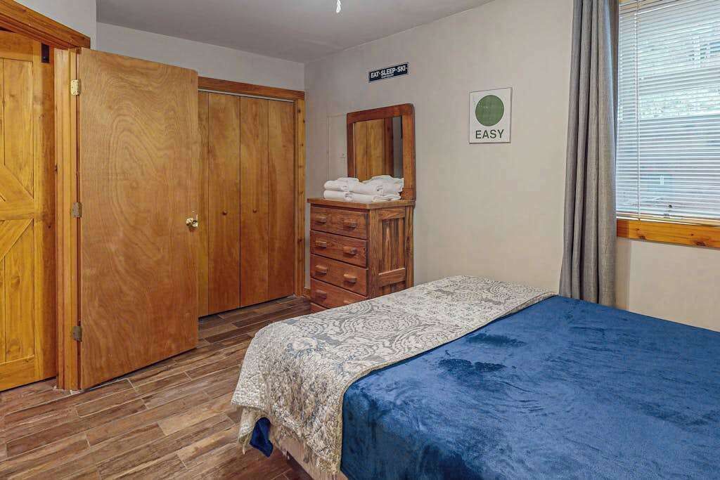 Een slaapkamer met een bed, een houten garderobe en een dressoir.