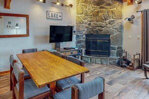 A cozy living room with a stone fireplace, a television, and a sign that reads 'LAKE'.