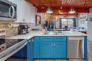 A modern kitchen with blue cabinets, a built-in oven, and a dishwasher. - 3BR - Lakeside Retreat - Pool (McHenry)