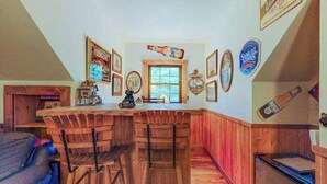 A kitchen with wooden bar stools, a wooden counter, and various wall decorations including framed pictures and a beer bottle.