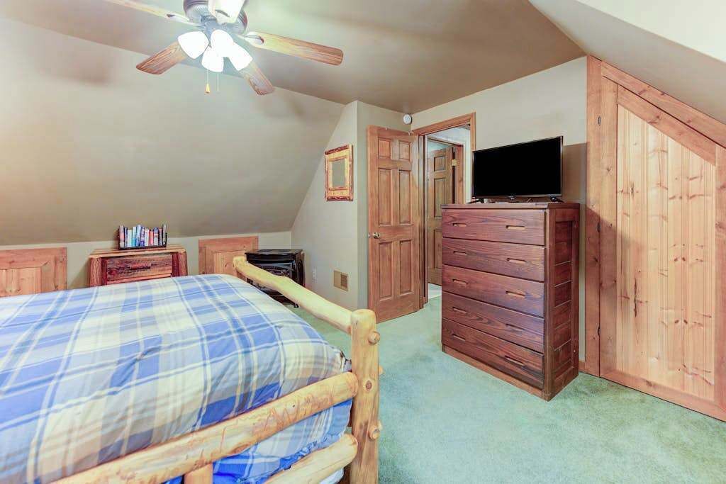 Ein Schlafzimmer mit Bett, Kommode, Fernseher und Deckenventilator.