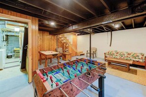 Una habitación con una mesa de fútbol, muebles de madera, un sofá y una escalera.