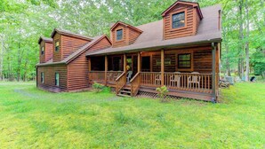 A log cabin with a porch, multiple windows, and a covered deck area.